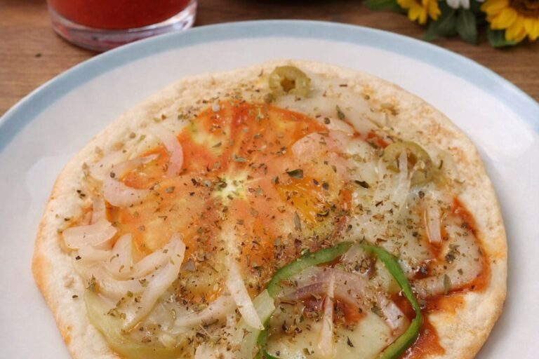 pizza redonda em um prato. a pizza tem tomate, cebola, pimentão, queijo vegano, molho de tomate e orégano.